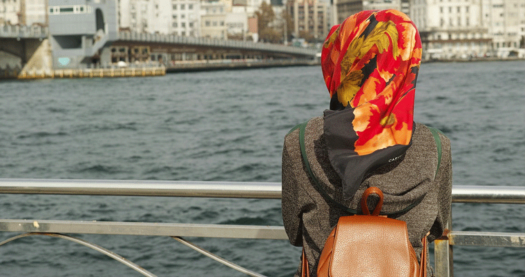 Muslimin mit Kopftuch auf Schiff blickt Wasser
