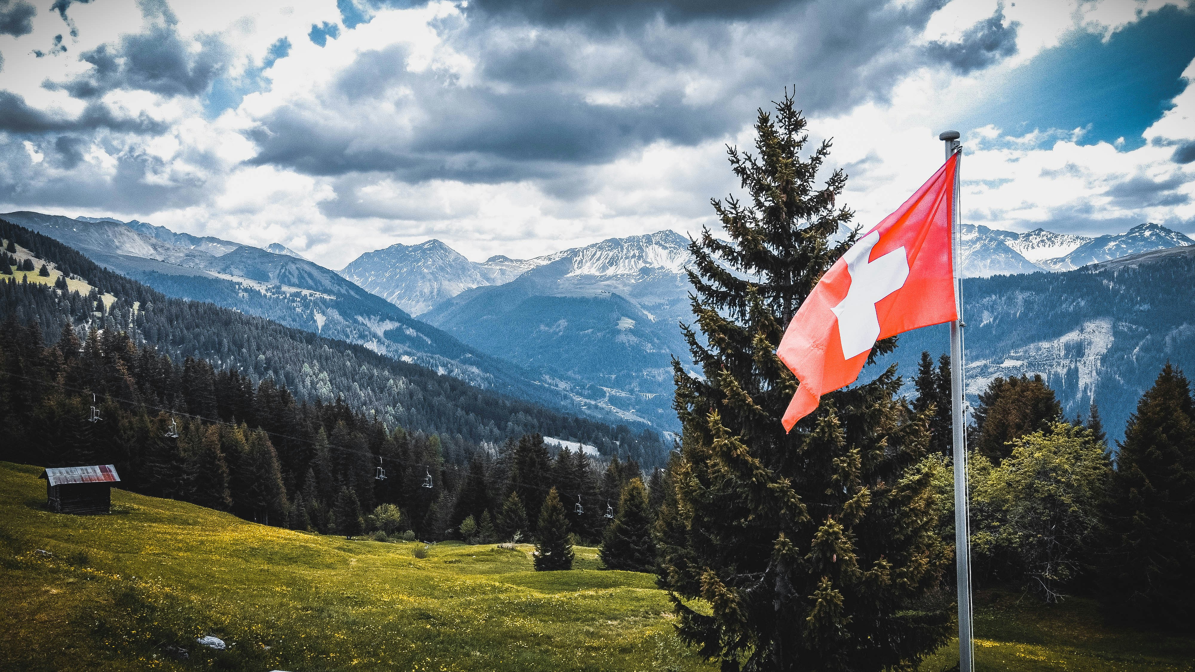 Schweizer Flagge vor Alpenpanorama – Sprachen und Dialekte in der Schweiz