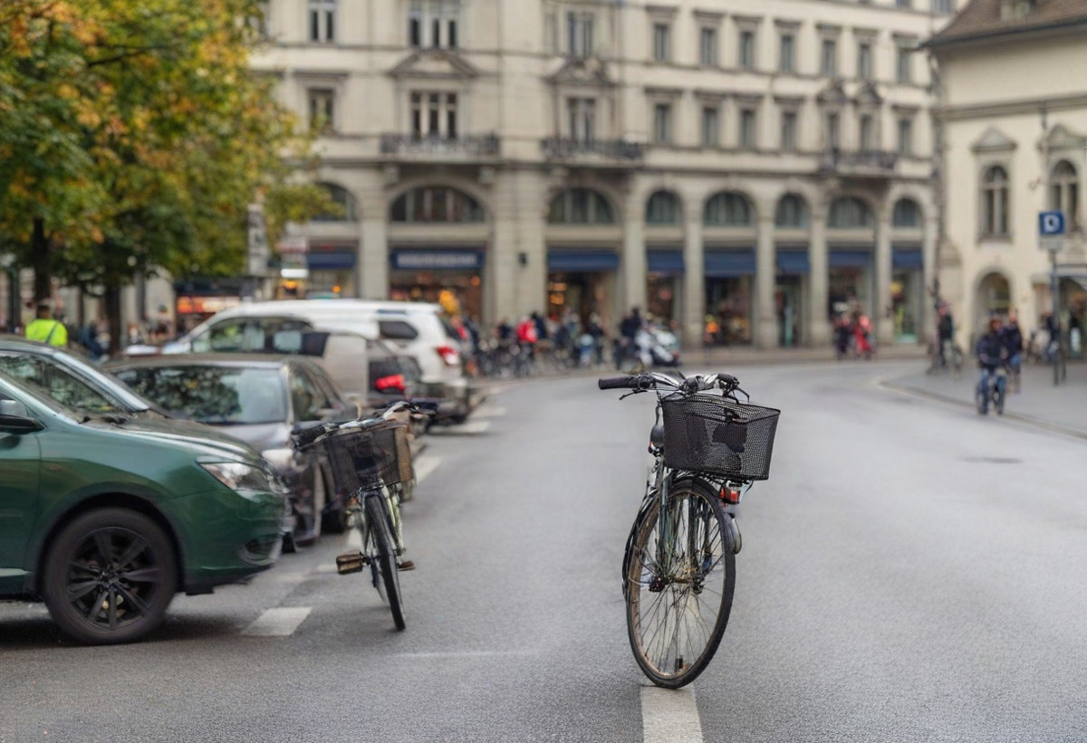 Strassenszene mit Fahrrädern und Autos, umgeben von historischer Architektur.